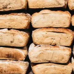 Stos chleba, który zastanawia, czy pies może jeść chleb. Każdy bochenek ma złocistą skórkę i lekko posypany mąką.