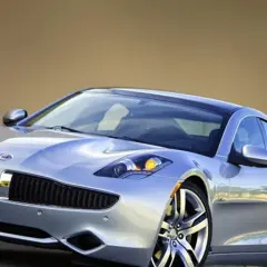 Srebrny Fisker Karma z charakterystycznym grillem i reflektorami, lśniącym lakierem i stylowymi felgami.