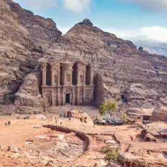 Niezwykłe miasto w skale Jordania, Petra, z monumentalną fasadą wykutą w piaskowcu. Turyści spacerują po piaszczystym placu u stóp starożytnej budowli.