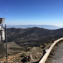 Vista panorámica desde la tetica de bacares, con un pluviómetro en primer plano y un paisaje montañoso y boscoso al fondo bajo un cielo azul.