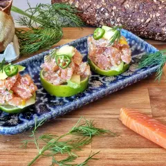 Tartar de salmón fresco servido en mitades de lima, adornado con aguacate y jalapeño.