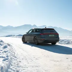 Audi A6 e-tron na śnieżnej drodze z górami w tle.