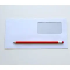 Czerwony ołówek leży na białej kopercie z okienkiem. Czas napisać, gdzie nadawca na kopercie.