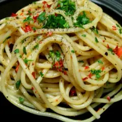 Pyszne spaghetti aglio e olio peperoncino, posypane natką pietruszki i pieprzem.