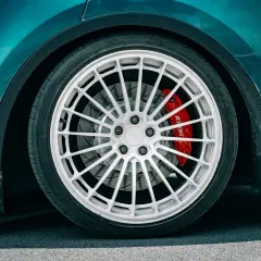 Detailaufnahme eines Autos mit auffälliger roter Bremsanlage. Der **Bremskolben fest** im Sattel deutet auf eine sportliche Performance hin.