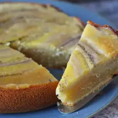 Un delicioso bizcocho de plátano, con una rebanada servida en un plato azul.