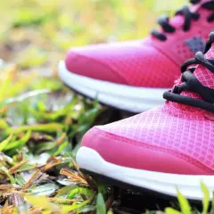 Rosa Laufschuhe mit schwarzen Schnürsenkeln auf Gras. Die richtige Wahl für welche Schuhe bei Kniearthrose?