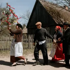 Ludzie w strojach ludowych niosą zieloną gałąź z wstążkami. Czy to symbol tego, ile trwa majówka?