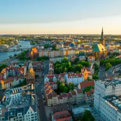 Widok z lotu ptaka na piękne Stare Miasto w Szczecinie, gdzie rzeka Odra przepływa przez miasto, a słońce zachodzi nad zabytkowymi budynkami.