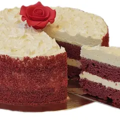 Un delicioso bizcocho red velvet con cobertura cremosa y una rosa roja decorativa. Una rebanada muestra sus capas rojas y blancas.