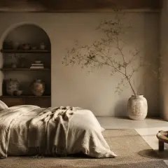 Sypialnia w stylu wabi sabi. Naturalne materiały, łóżko z lnianą pościelą, łukowa wnęka z ceramiką i gałązka w wazonie.