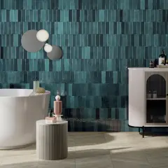 Une salle de bain moderne avec des carreaux muraux bleu sarcelle profonds, une baignoire îlot blanche et un meuble de rangement élégant. Une belle idée couleur salle de bain pour une ambiance chic.