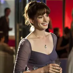 Anne Hathaway w filmie, uśmiechnięta, trzymająca drinka.