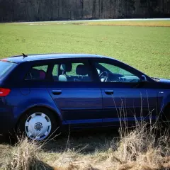 Granatowe Audi 8P na tle zielonego pola i lasu.