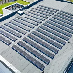 Nowoczesny dom z płaskim dachem pokryty rzędami paneli słonecznych, które czerpią energię ze słońca.