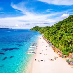 Piękna plaża na Filipinach, gdzie turkusowa woda i biały piasek tworzą rajski widok. Nawet podczas pory deszczowej, słońce przebija się przez chmury, zapraszając do relaksu.