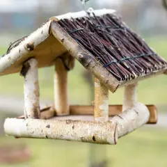 Ein selbstgebautes vogelfutterhaus aus Holz und Zweigen, bereit für gefiederte Gäste.