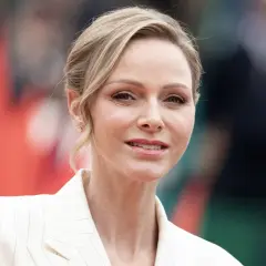 La princesa de Mónaco, Charlene Wittstock, sonríe con un traje blanco a rayas.