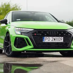 Jaskrawozielone Audi RS3 z czarnymi felgami i detalami, zaparkowane na mokrym asfalcie.