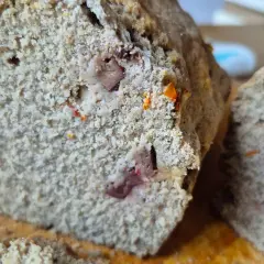 Rebanada de pan sin gluten con trozos de frutos secos y un toque anaranjado.