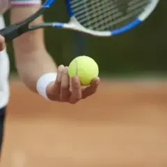 Gracz trzyma piłkę tenisową, gotowy do serwisu. Kluczowy moment w tie breaku.