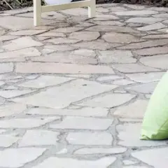 Naturalny chodnik z płyt chodnikowych, idealny do relaksu na świeżym powietrzu. Dwie poduszki, jedna jasnozielona, dodają koloru.