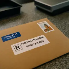 Brązowa koperta z naklejką "PRIORYTET PRIORITY" i etykietą "PRZESYŁKA POLECONA" z numerem. Czy przesyłka polecona to list? Tak, to list polecony.