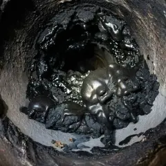 Gros amas de suie et de goudron fondu, vestiges d'un feu de cheminée.