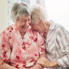 Zwei lachende Seniorinnen, die sich umarmen. Ein schönes Beispiel, wie man neue Freunde finden ab 60 kann.
