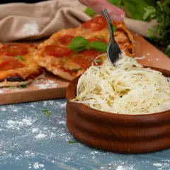 En skål med krispig pizzasallad bredvid en pizza med tomater. Perfekt tillbehör för ditt pizzasallad recept.