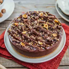 Delizioso cheesecake alla nutella, ricoperto di riccioli di cioccolato e nocciole tostate.