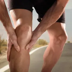 Biegacz trzyma się za bolesne kolano, być może z powodu urazu MCL.