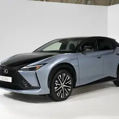 Elegancki, niebieski Lexus RZ 450e z czarnym dachem i futurystycznymi felgami stoi na białym tle.