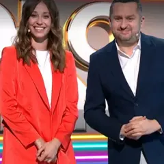 Uśmiechnięta kobieta w czerwonej marynarce i mężczyzna w granatowym garniturze na tle logo "Koło Fortuny".