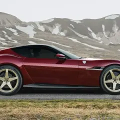 Czerwone Ferrari LaFerrari z złotymi felgami na tle górskich krajobrazów.
