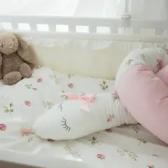 En söt sovorm med blomstermönster och en nalle i en spjälsäng.