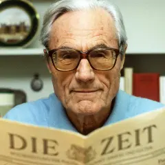 Gerd Bucerius, mit Brille und einem Lächeln, liest die Zeitung "DIE ZEIT".