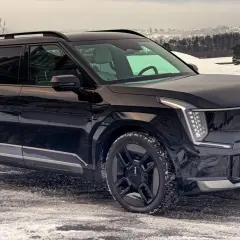 Svart Kia EV9 på en snöig väg, redo för ett vintertest. Bilen har en modern design med distinkta LED-lampor.