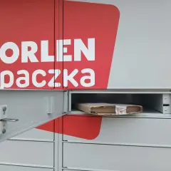 Szafka paczkomatu z logo Orlen Paczka i paczką w środku.