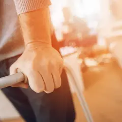 Dłoń osoby podtrzymującej się chodzika. Umiarkowany stopień niepełnosprawności a renta rodzinna – wsparcie dla potrzebujących.