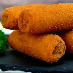 Chrupiące krokiety z pieczarkami i serem, idealne na przekąskę. Obok plaster cytryny i natka pietruszki.