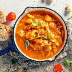 Eine dampfende, traditionelle italienische Suppe mit Gemüse und Pasta, serviert mit frischem Brot und Tomaten.