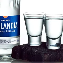 Butelka wódki Finlandia i dwa kieliszki z wódką na ciemnym tle.