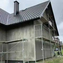 Dom w trakcie prac elewacyjnych, rusztowania wokół ścian. Zastanawiasz się, ile kosztuje elewacja domu?
