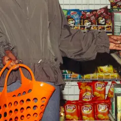Person mit Einkaufskorb vor Chipsregal. Die **skimpflation definition** zeigt, wie Hersteller bei gleichbleibenden Preisen die Menge reduzieren.