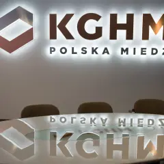 Logo KGHM Polska Miedź i odbicie na stole. Czy Konfederacja poprze ustawę o obniżeniu podatku miedziowego w zamian za ustępstwa?