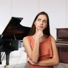 Kobieta zastanawia się, czy pianino jest instrumentem strunowym, stojąc między fortepianem a pianinem pionowym.