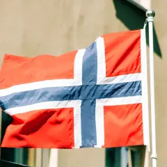 Norweska flaga powiewa na wietrze. Zastanawiasz się, ile zarabia programista w Norwegii?