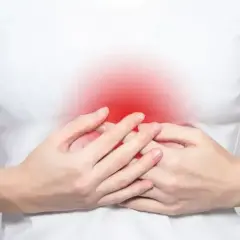 Dłonie obejmujące brzuch, gdzie czerwony obszar symbolizuje ból w splocie słonecznym.