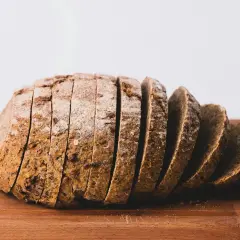 Pokrojony chleb żytni na drewnianej desce. Idealny na zdrowe śniadanie, choć warto pamiętać o jego kcal.